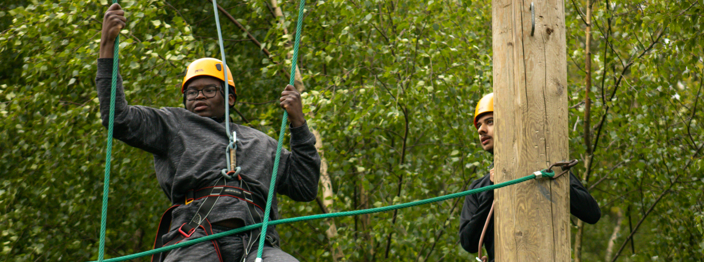 Two people wearing yellow helmets holding on to ropes.