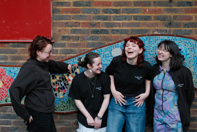 4 people wearing Caxton Youth uniforms laughing outdoors.