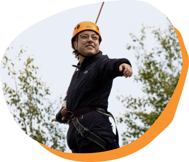 A person wearing an orange helmet and a harness.