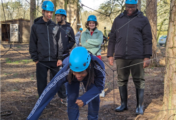 A group of 5 people wearing blue helmets in a forest.