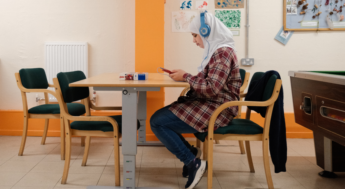 A young person wearing headphones sitting at a table in Caxton youth club.