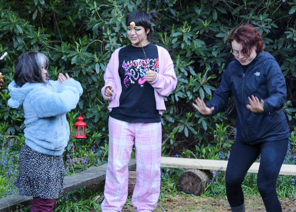 3 people dancing in a forest.