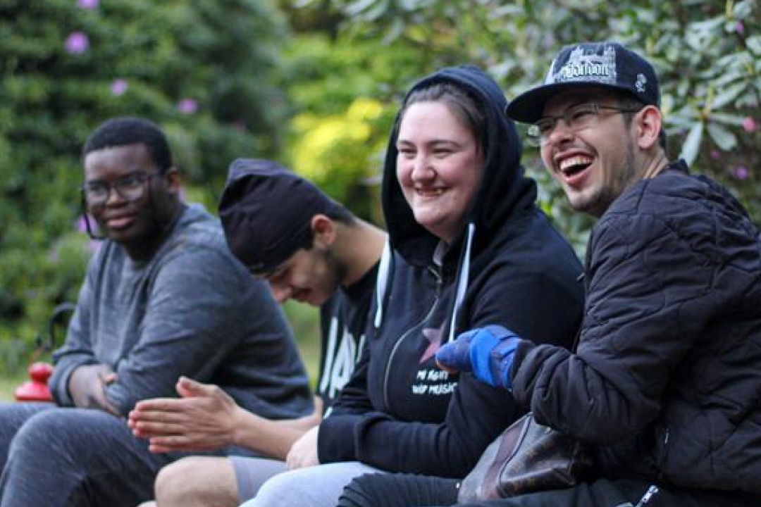 4 young people laughing in an outdoor setting.