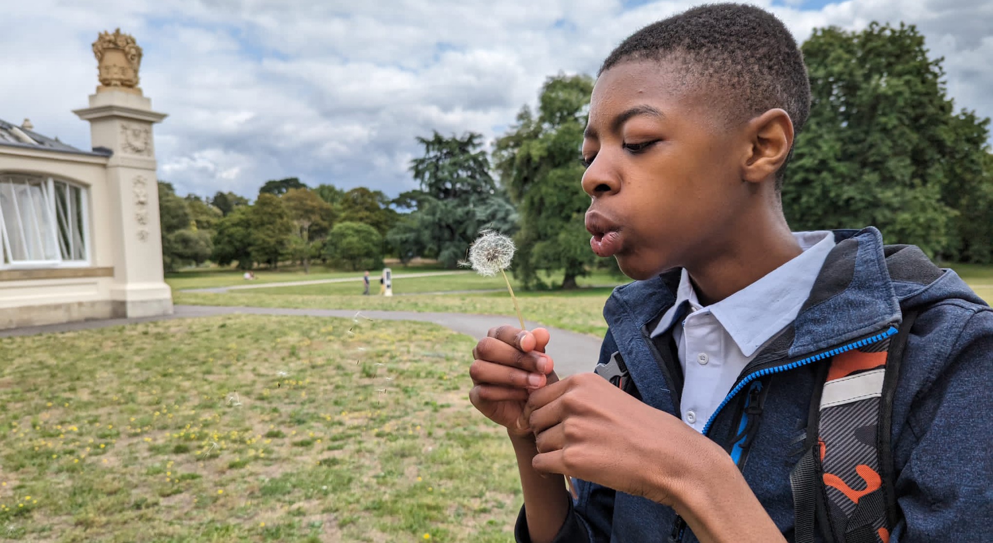 A young person blowing a dandelion.