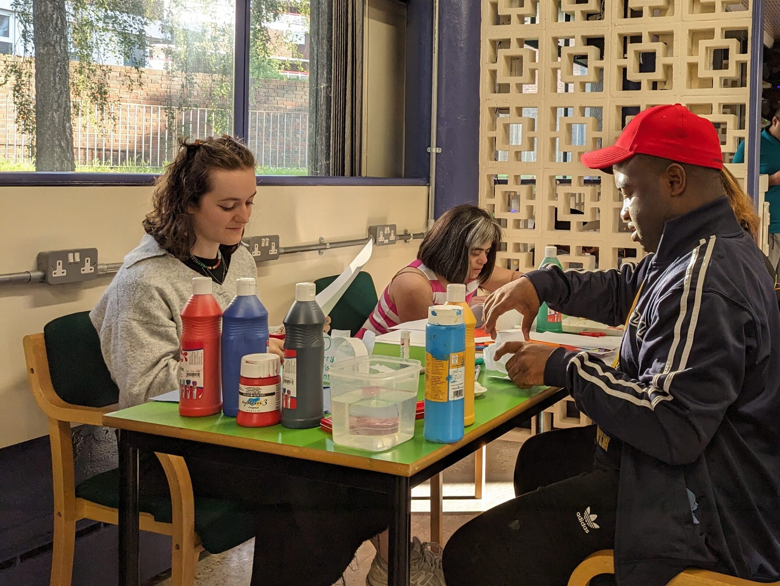 Three people sitting at a table making art. There