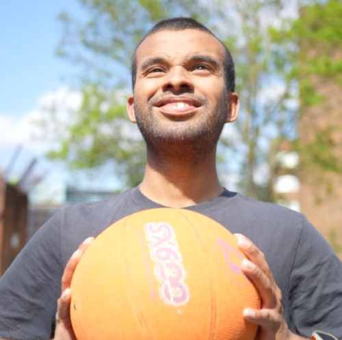 A young man about to throw a basketball with both hands outside.